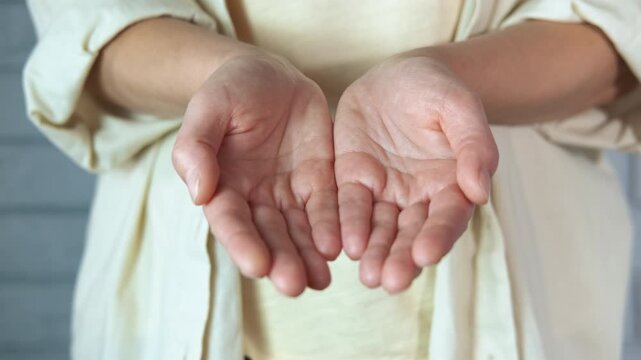 Woman opening hands. Midsection shot of a woman with her arms outstretched, slowly opening her cupped hands in a welcoming, giving, or begging gesture, with palms facing up towards the camera