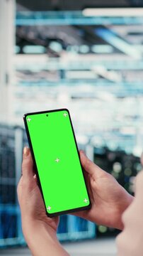 Vertical video Mockup smartphone used by server room IT expert to optimize rigs. Data center female engineer using isolated screen mobile phone to monitor equipment performance and fix bottlenecks