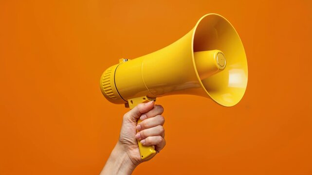 Amplified Voice: A hand firmly grasps a vibrant yellow megaphone against an orange backdrop, symbolizing a call to action or announcement. 