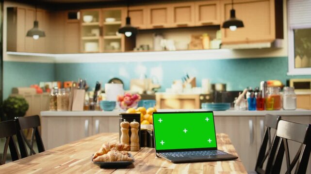Green screen laptop, rustic kitchen interior, wooden breakfast table for coffee and pastry. Bright natural light and warm tones, appliances and kitchenware in cozy open space, interior design.