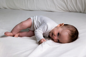 Happy healthy baby infant smiling rolling playing on bed