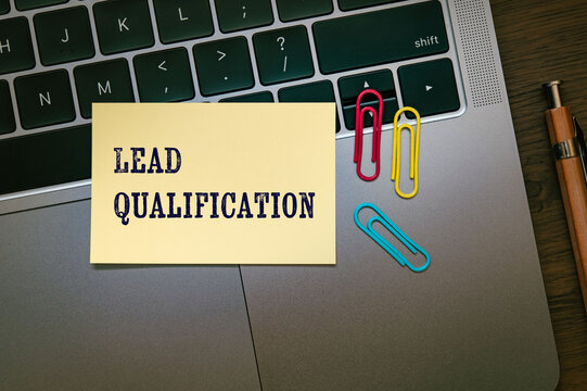 Business concept of Lead Qualification represented on sticky note with laptop, clips. Ideal for marketing and promotional content.