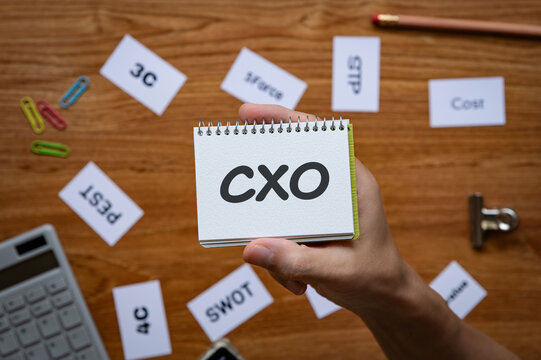 Eye-catching image of CXO text on notebook. The word stands for Chief user eXperience Officer. Shown with calculator, clips.