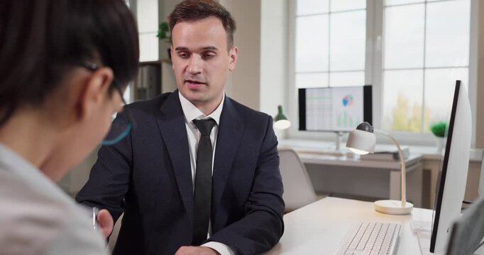Manager colleague consulting in office by computer. At the desk, the manager reviews charts and documents, giving feedback on briefing goals in a workspace. Teamwork and leadership in business.