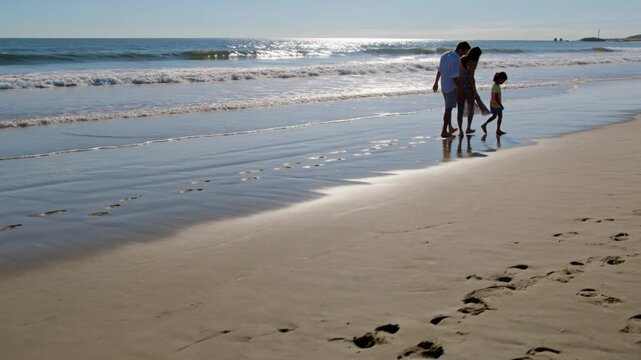 Young family with child walking on sandy beach
