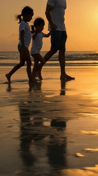 Silhouette of father walking with daughters on beach at sunset