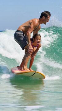 Father and daughter surfing on a wave together