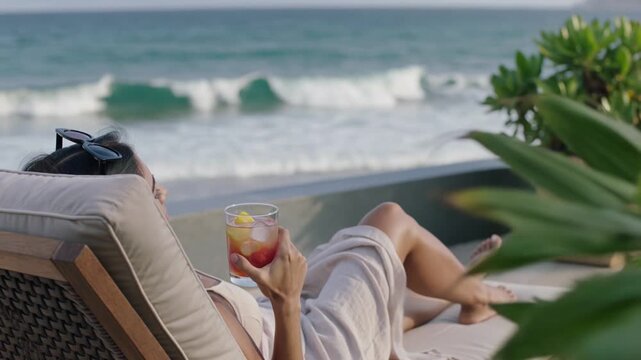 Woman relaxing with cocktail on lounger enjoying ocean view