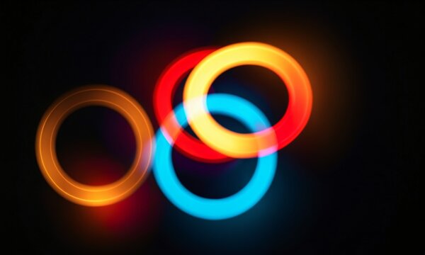 overlapping glowing circular light rings in blue yellow and red colors on a black background with soft light glow.