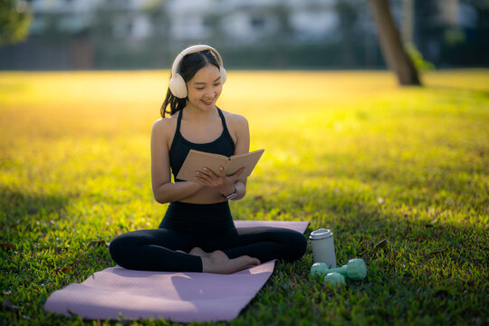 Young woman enjoying book and music in park