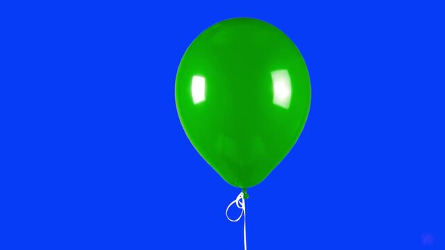 A classic green rubber balloon with a high-shine finish floating against a solid blue studio background. Suitable for environmental themes, festive designs, or children's holiday content.