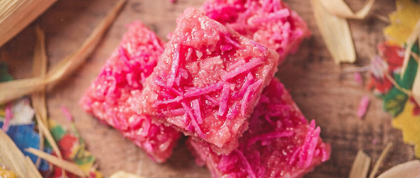 A close up of a pile of pink rice krispy treats on a wooden surface surrounded by colorful confetti