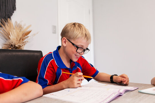Boy smiling at workbook completing homework assignment for school