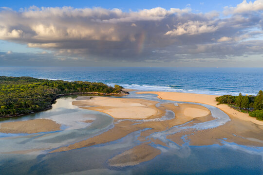Aerial view of an inland lake draining out through tidal channels and narrow opening to the sea