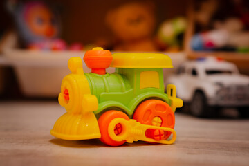 Colorful plastic toy train standing on the floor in a child room. Locomotive model for play. Childhood fun, imagination, creative development and early education for toddler concept.