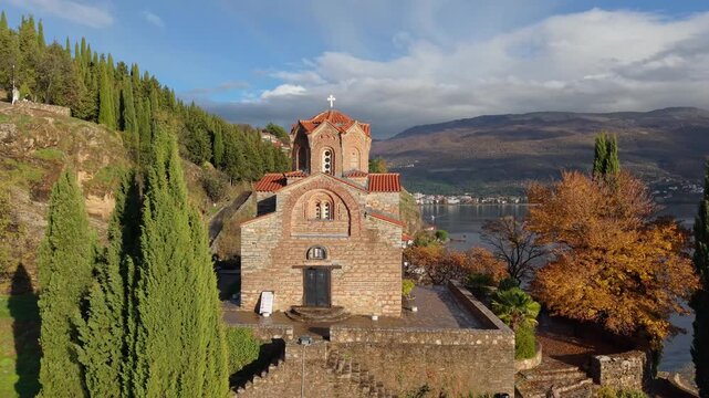 Drone ascending from the Church of Saint John at Kaneo, gradually revealing Ohrid, the surrounding landscape, and the lake, highlighting Byzantine architecture and scenic Balkan views.