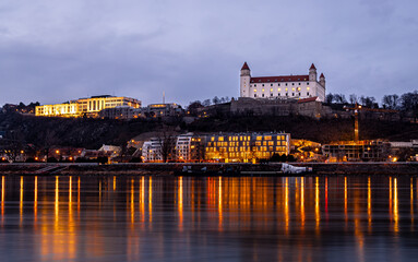 Obraz premium Bratislava Castle at dusk above the Danube with city lights in Slovakia