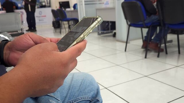Young man sitting while scrolling his phone