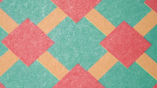 Dynamic multicolored checkered pattern with slow rotation for creative designs, Graphic background with green and red squares in a rotating motion