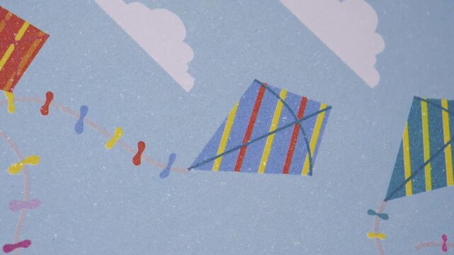 Close up pan of colorful kite and cloud pattern on blue paper, Smooth camera movement over textured blue paper with kite design