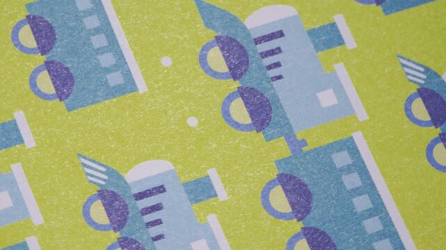 Close up pan of colorful train and steam engine pattern on green paper, Playful locomotive background with blue toy train illustrations