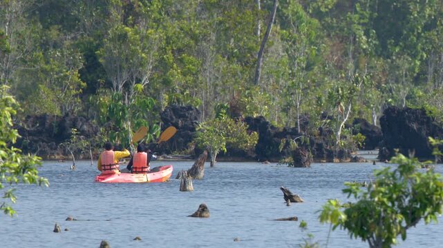 Two People Paddling an Orange Kayak Through a Mangrove Forest in Krabi