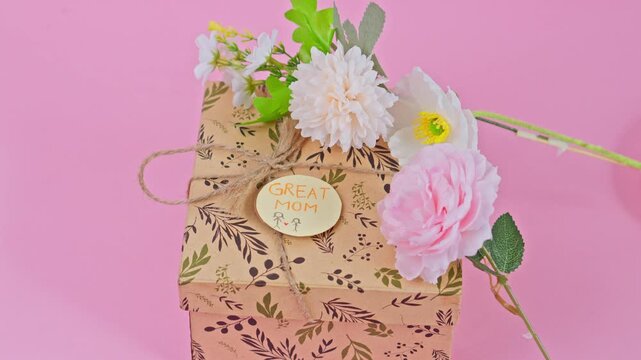 Celebratory gift box decorated with elegant faux flowers and 'Great Mom' label