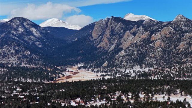 Estes Park Rocky Mountains National Park mountain town Lumpy Ridge Twin Owls rock formation Mummy Range Colorado aerial drone valley landscape sunset fresh snow clouds blue sky sunny forward pan up