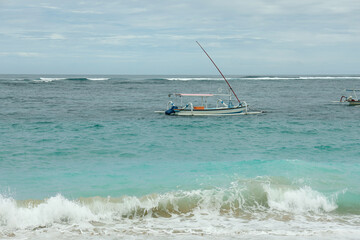 A fishing boat navigates through the ocean waves in Bali