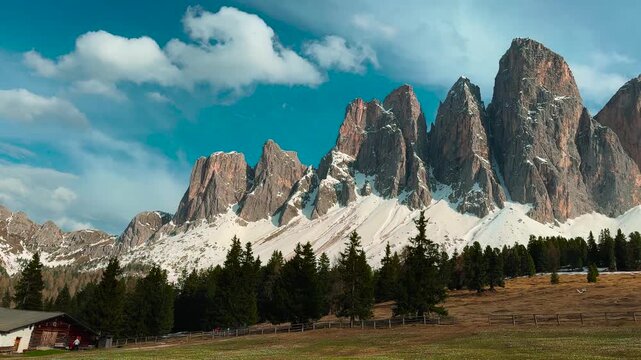 Towering Dolomite rock formations with alpine pasture and conifer trees in spring, Glatschalm area, Italian Alps
