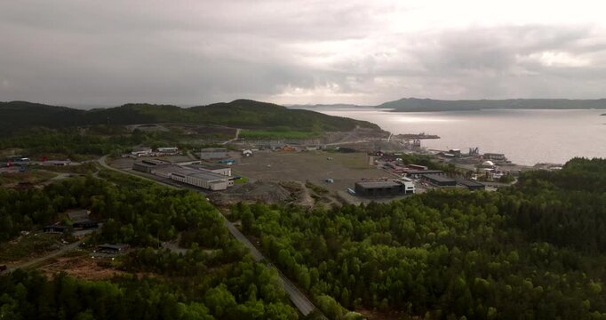 Aerial view of the quartz diorite quarry at Normdarka, Norway, showing industrial stone extraction beside forest and calm coastal water under moody sky