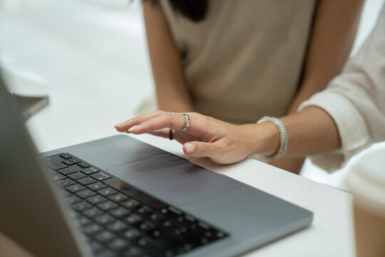 Woman's hand using laptop trackpad, working remotely