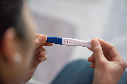 Woman holding positive pregnancy test revealing motherhood concept