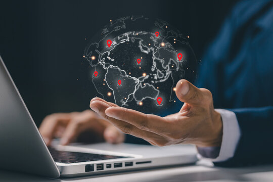 Businessman holding digital globe with location pins representing global logistics network and international business expansion. Concept of worldwide trade, supply chain, transportation