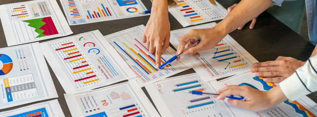 Close up of business consultant team hands pointing at data summary charts with pens on table,...