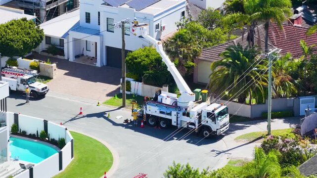 Utility Worker in Cherry Picker Repairing Power Lines on Residential Street