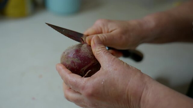 Hands Peeling Beetroot with Knife in Kitchen