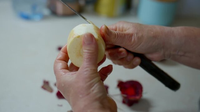 Hands Peeling Celery Root with Knife in Kitchen