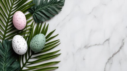 Fototapeta premium A flat lay arrangement featuring three speckled Easter eggs in pastel pink white and mint green artfully placed among vibrant tropical leaves on a smooth white marble background