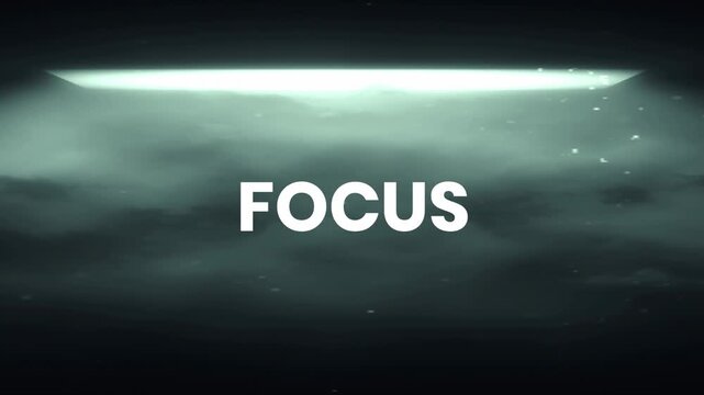 The word "focus" emerges powerfully in white against a dramatic, smoky, dark background, illuminated by a bright, horizontal light source, with tiny particles gracefully drifting through the air in th