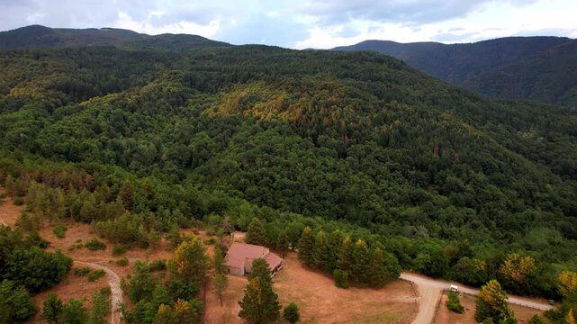 Backward drone flight revealing Madonna di Montalto chapel. Long shadows and parallax effect between the church clearing and distant peaks