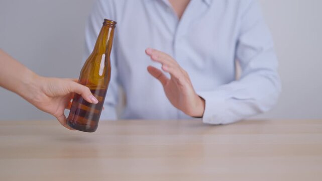 man making stop hand gesture to refuse a bottle of Beer, Healthy man say no to alcohol drink, stop alcoholism and addiction concept. Responsible man reject a drink before driving and quit booze