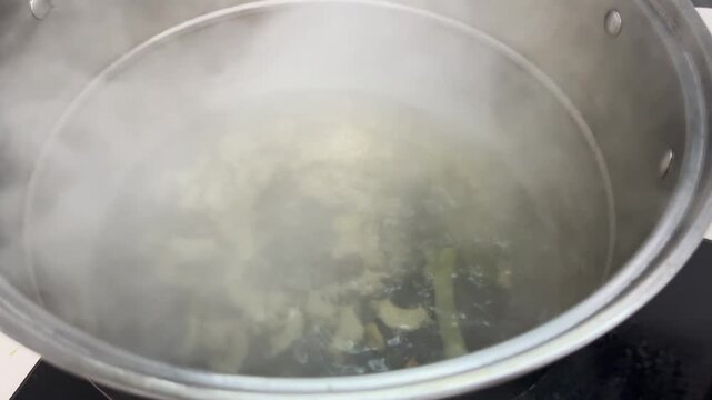 Cooking food in a wok at home kitchen, with pieces of battered ingredients deep frying in hot oil while being stirred with a metal spatula, showcasing energetic Chinese home cooking in Xi'an, China.