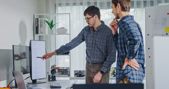 Team adult male engineer collaborate on robotic hand project using AI code solutions machine learning at tech workspace. Artificial intelligence interface, collaboration support prototype development.
