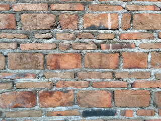 Obraz premium Texture of an old red brick wall with visible cement mortar and weathered surfaces. This rustic architectural background showcases traditional masonry craftsmanship in a vintage urban style.