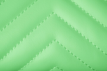 Fototapeta premium Detailed vibrant light green quilted leather texture featuring a clean stitched chevron pattern background