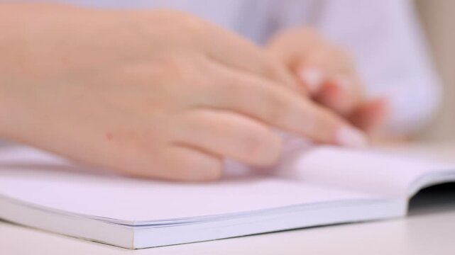 Hand is touching a white piece of paper. The paper is folded in half