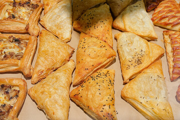 Freshly baked golden brown savory puff pastries with black seeds and mushroom filled tarts