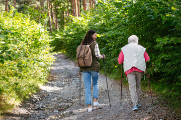 Fototapeta premium Senior woman and daughter enjoying hike with trekking poles.