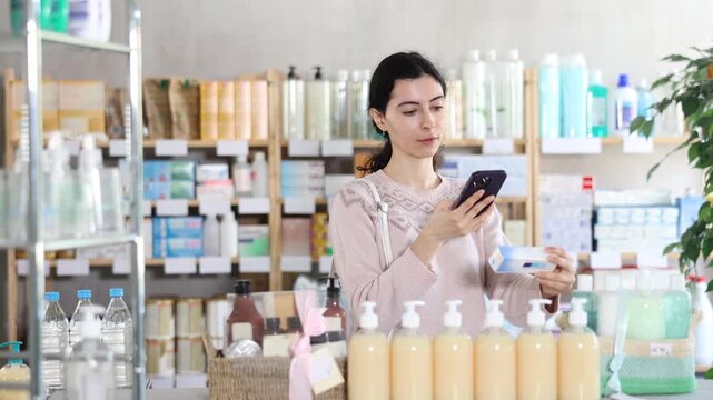 Young woman buyer scanning qr code for box of ointment in pharmacy 